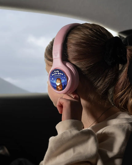 A child wearing ONANOFF pink Disney StoryPhones with Kids Audio Bible Old Testament StoryShield, listening to stories about Abraham and Issac. The girl looks out a car window at a distant mountain.